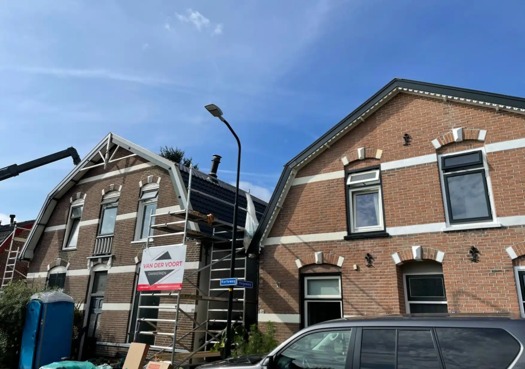 Dakrenovatie in Apeldoorn: woningen in de steigers met bouwbord van Van der Voort Dakwerken