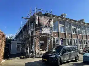 Pand in Ede in de steigers met spandoek van Van der Voort Dakwerken tijdens dakrenovatie