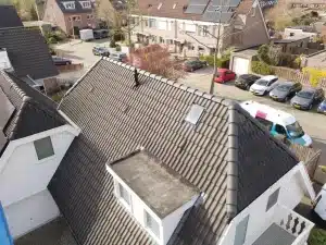 Bovenaanzicht van een donker pannendak met nokvorsten en dakraam bij een woning in Ede