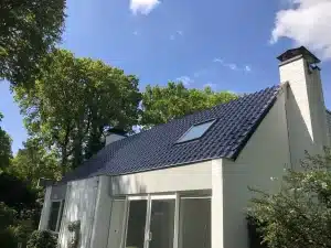 Vernieuwd donker pannendak met dakraam op een witte woning in Otterlo