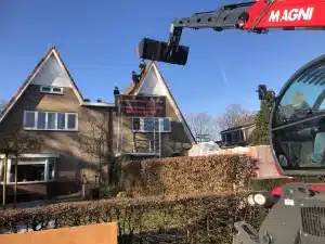 Verreiker hijst materiaal naar de nok van een woning in Otterlo tijdens de dakwerkzaamheden