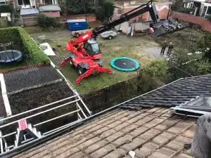 Zicht vanaf het gestripte dak op de verreiker in de achtertuin tijdens de dakrenovatie in Wageningen
